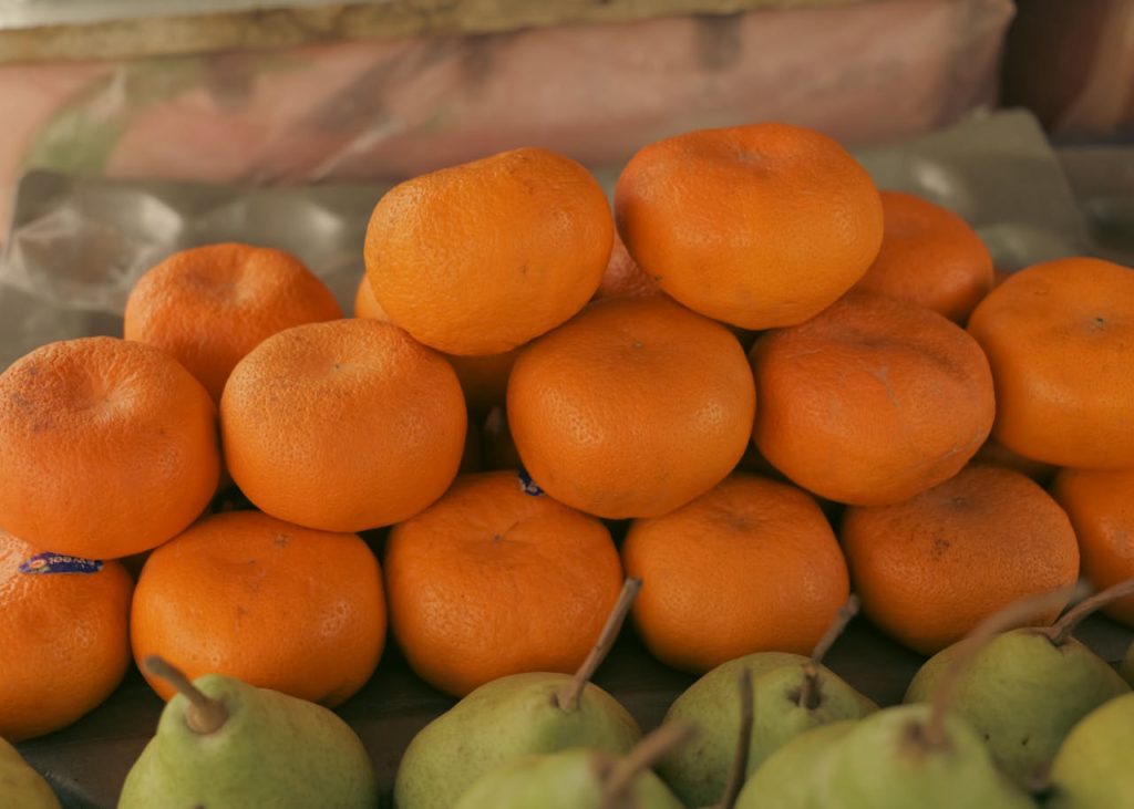 Fresh oranges and pears displayed at a market stall, showcasing vibrant colors and natural textures.