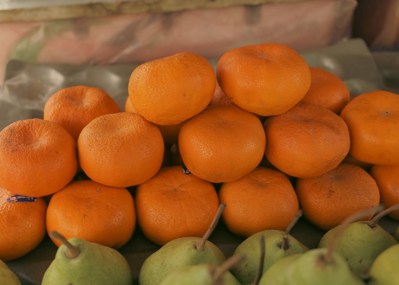 Fresh oranges and pears displayed at a market stall, showcasing vibrant colors and natural textures.